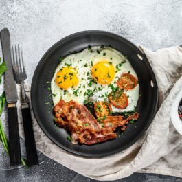 O masă pe care se află o tigaie cu o ouă ochiuri pentru a ilustra alimentele bogate în proteine