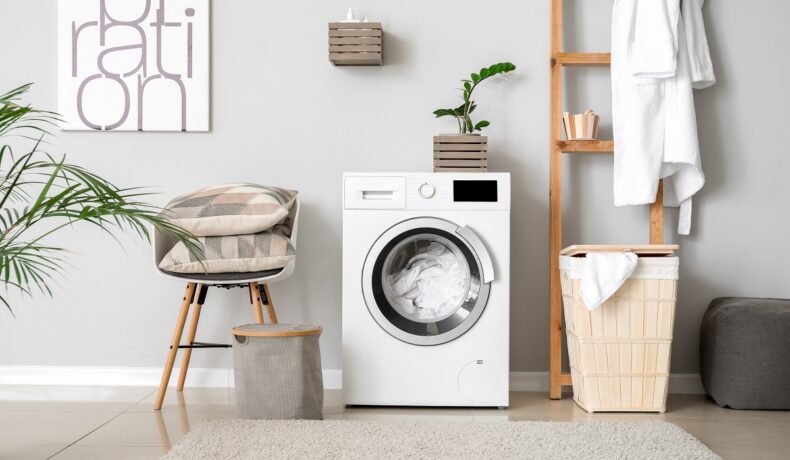 O mașină de spălat alături de un coș de rufe pentru a ilustra principalele lucuri pe care nu știai că le poți curăța la mașina de spălat