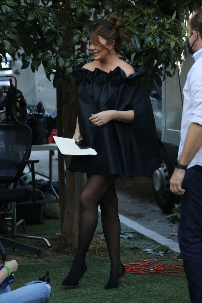 Chrissy Teigen, elegantă, într-o rochie curtă, la filmările pentru o emisiune TV