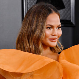 Chrissy Teigen, într-o rochie portocalie, la Grammy