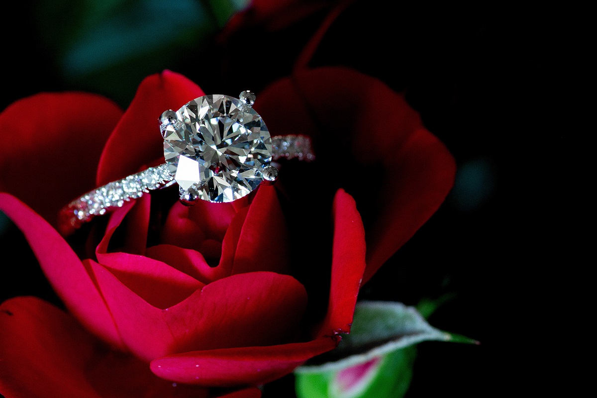 Un inel de logodnă cu diamant prins de un trandafir roșu
