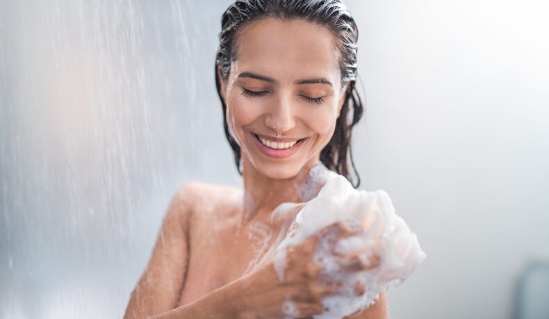 O femeie frumoasă care își face duș cu spumă