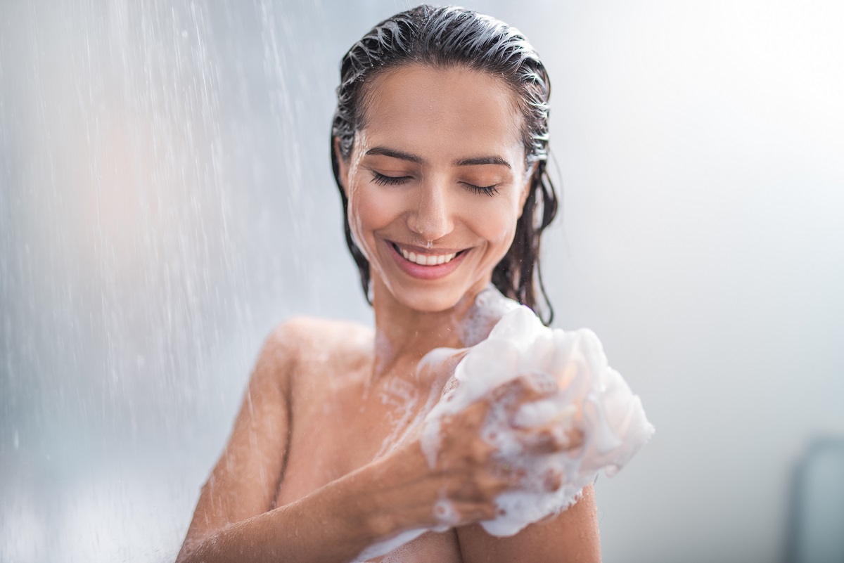 O femeie frumoasă care își face duș cu spumă