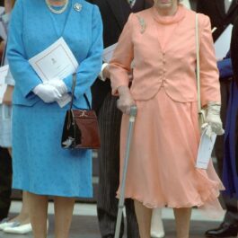 Regina Elisabeta într-un costum albastru alături de sora sa, Pprințesa Margaret, ntr-un costum orange