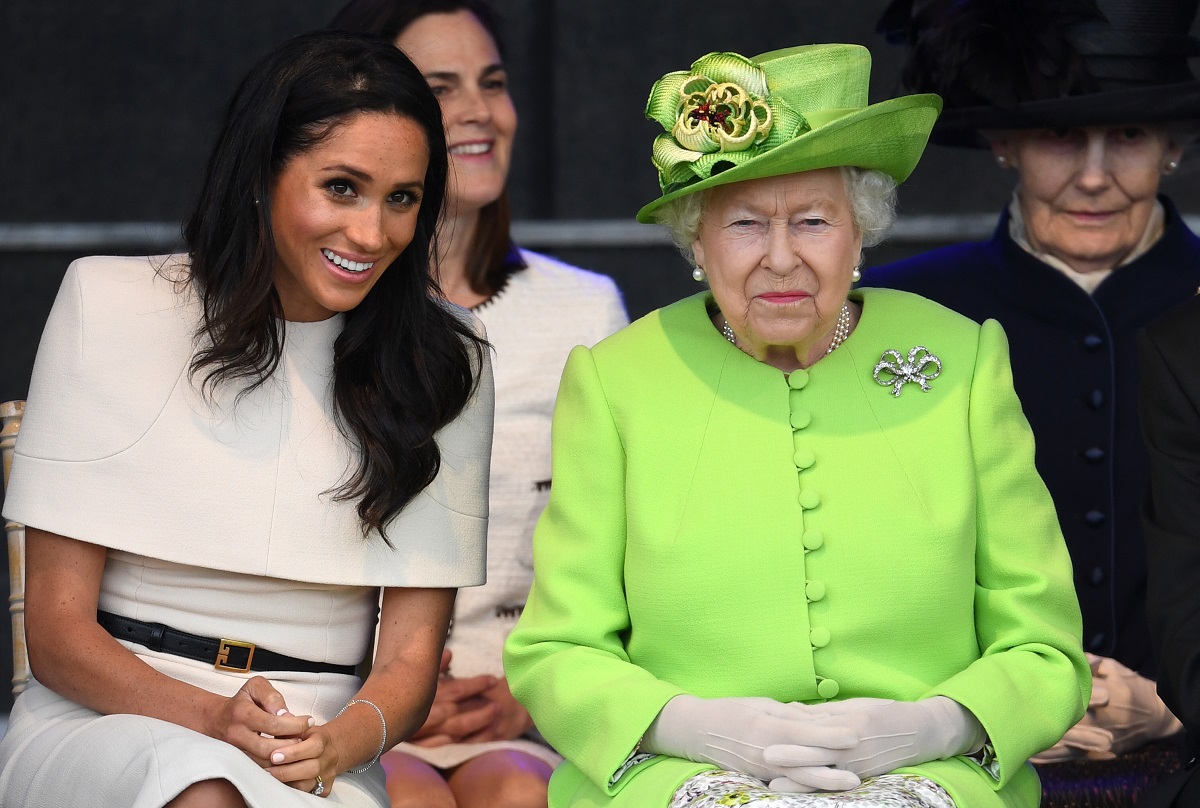 Meghan Markle într-un costum alb alături de Regina Elisabeta care poartă un costum verde