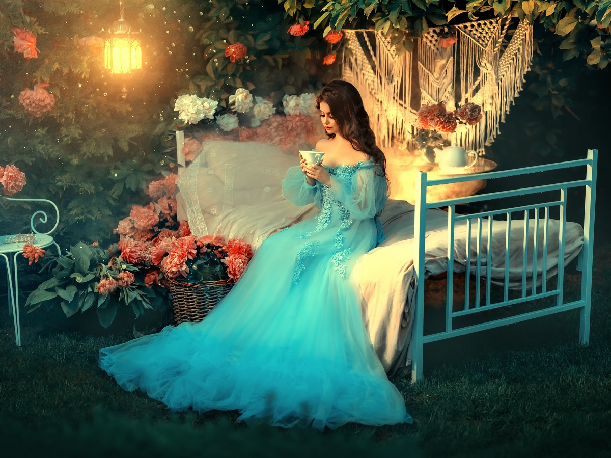 O femeie frumoasă îmbrăcată într-o rochie albastră care stă pe un pat pentru a reprezenta una din cele trei zodii norocoase