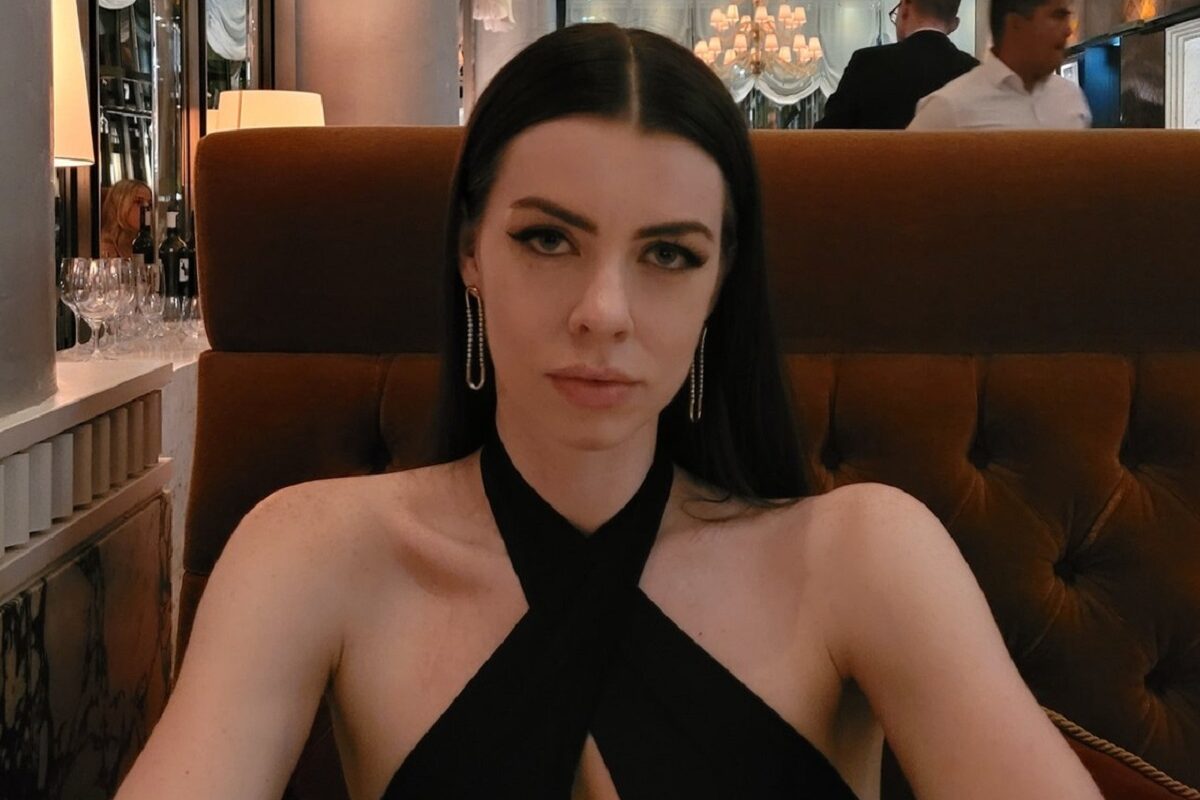 Cherie Louise într-o rochie neagră în timp ce pozează la un restaurant