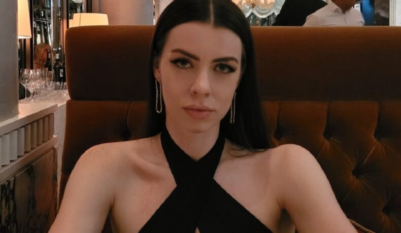Cherie Louise într-o rochie neagră în timp ce pozează la un restaurant