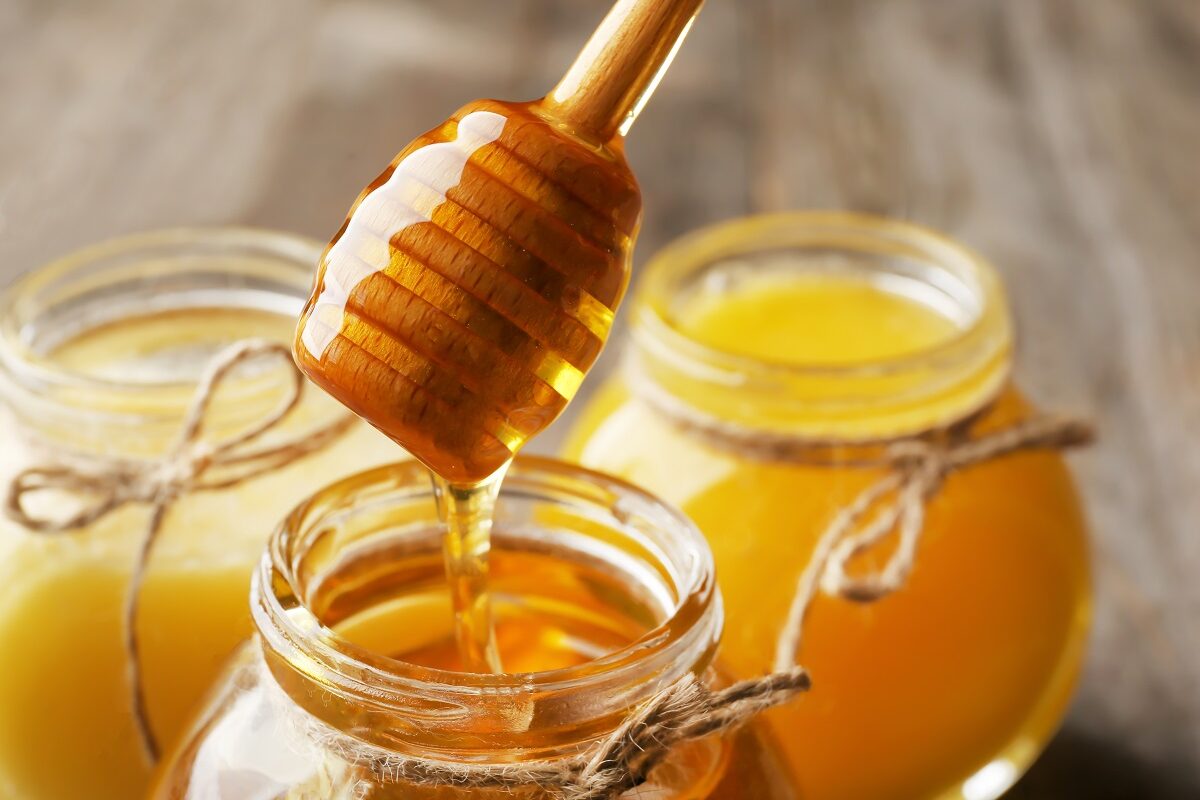 Trei borcane cu miere în care se află și o linguriță specială pentru a ilustra ce se întâmplă în corpul tău după ce consumi două lingurițe de miere în fiecare zi