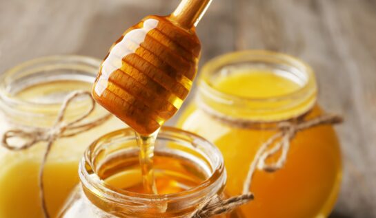 Trei borcane cu miere în care se află și o linguriță specială pentru a ilustra ce se întâmplă în corpul tău după ce consumi două lingurițe de miere în fiecare zi