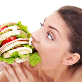 O femeie care încearcă să mănânce un sandviș imens