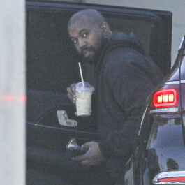 Kanye West, îmbrăcat în negru, cu o cafea în mână