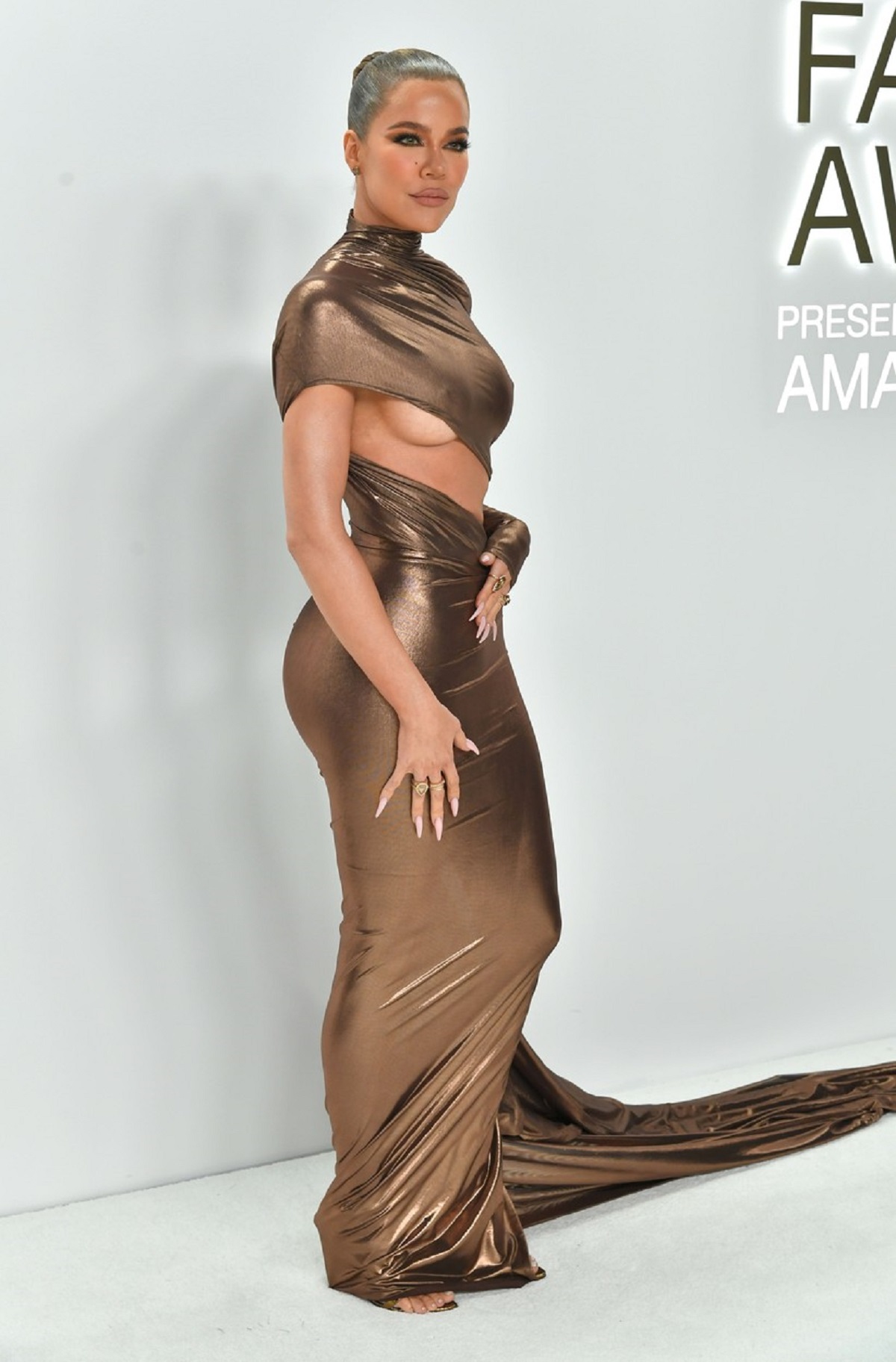 Khloe Kardashian într-o rochie mualtă aurie în timp ce pozează la CFDA Fashion Awards