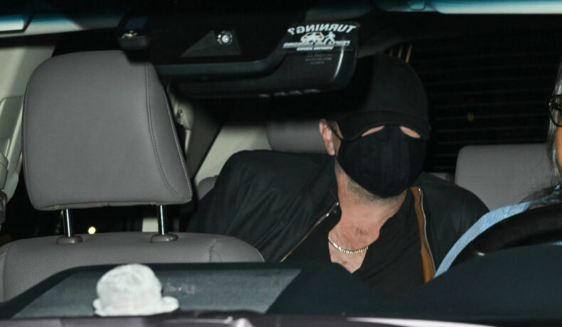 Leonardio DiCaprio, pe bancheta din spate a unei mașini, cu fața acoperită