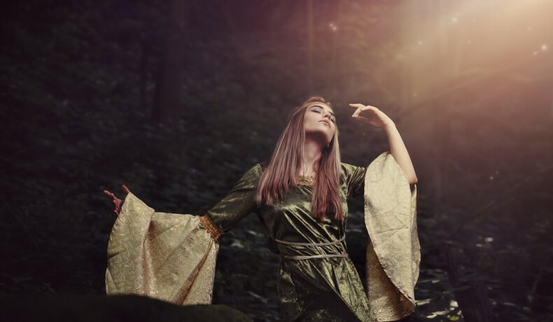Fată frumoasă îmbrăcată într-o rochie lungă stă în pădure