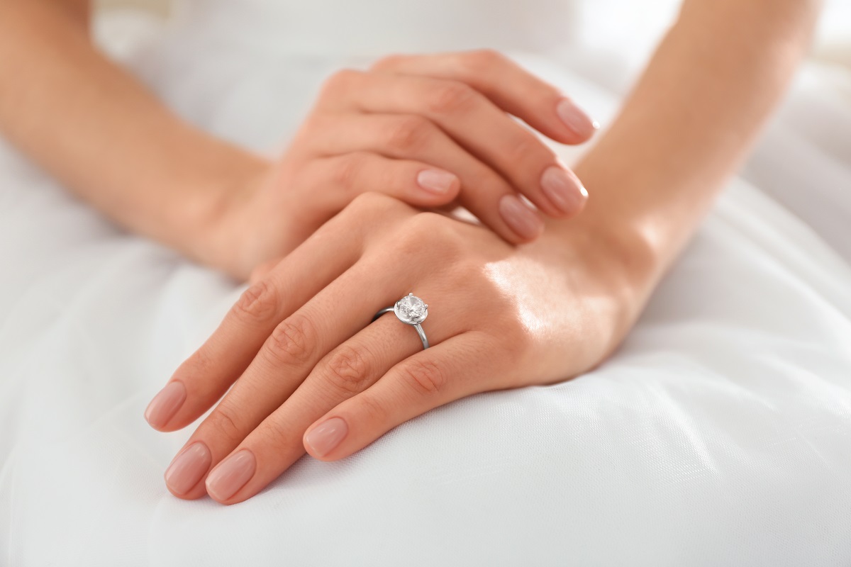 O femeie care își arată inelul de logodnă pentru a ilustra motivul pentru care inelul de logodnă se poartă pe degetul inelar