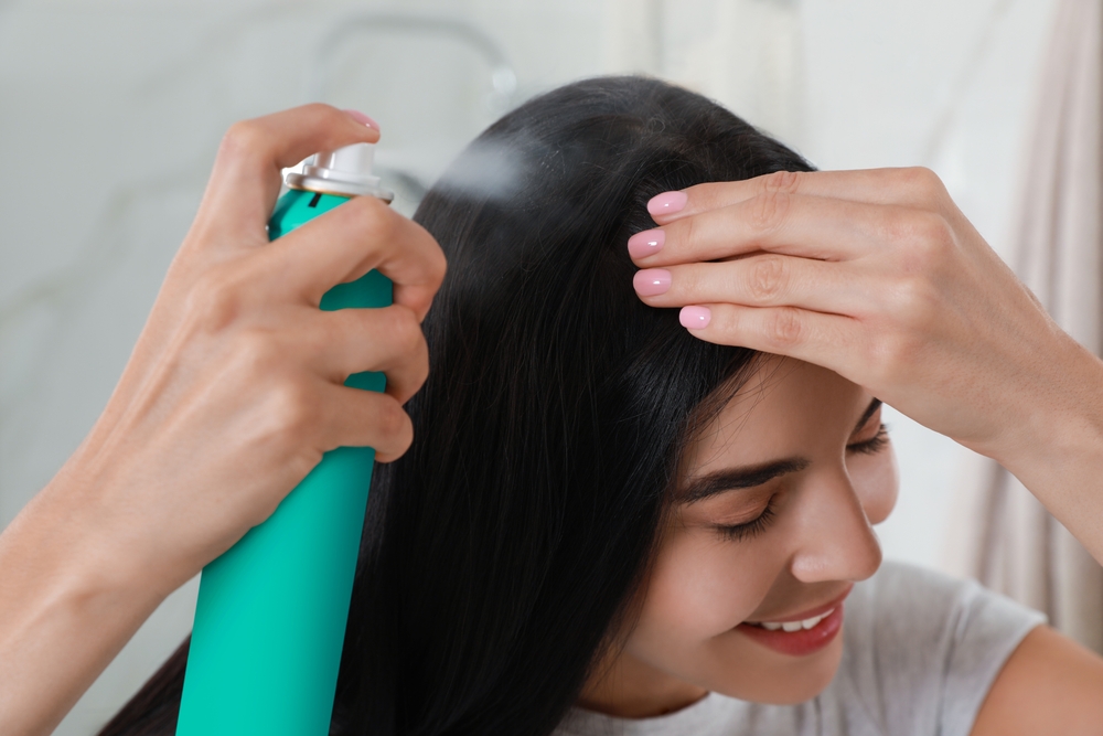 O femeie care aplică șampon uscat pe păr