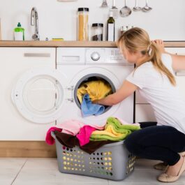 O femeie care bagă rufe la mașina de spălat rufe