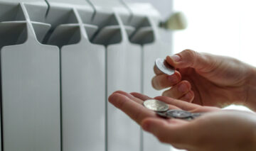 O femeie care numără banii lângă calorifer
