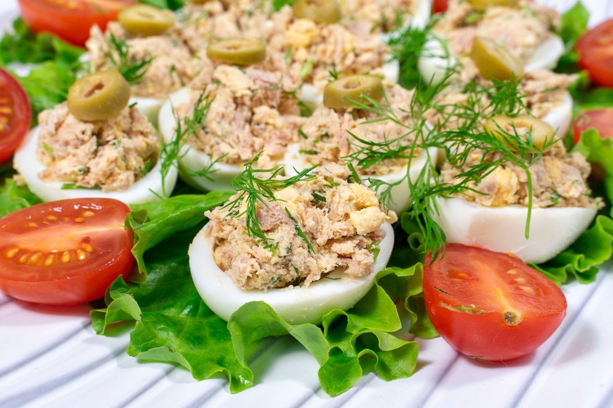 Ouă umplute cu pastă de ton pe un platou cu salată verde, decorate cu mărar