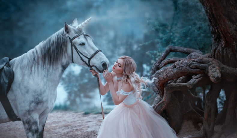 Fată frumoasă îmbrăcată într-o rochie de prințesă este în pădure lângă un cal