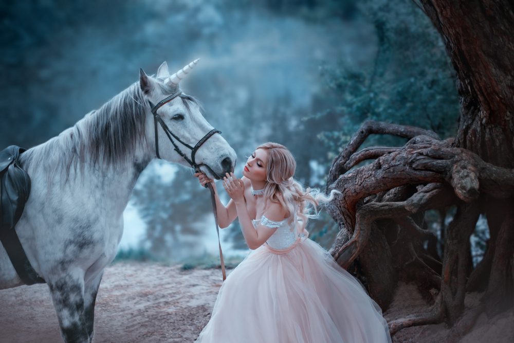 Fată frumoasă îmbrăcată într-o rochie de prințesă este în pădure lângă un cal