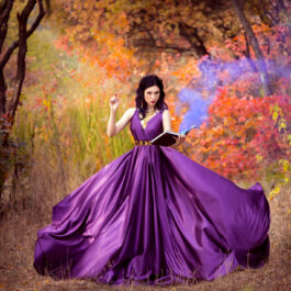 Fată frumoasă îmbrăcată într-o rochie mov stă în pădure