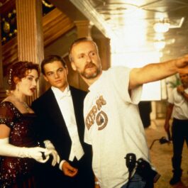Kate Winslet, Leo Dicaprio și James Cameron se află pe platourile de filmare ale „Titanic” și cei doi actori poartă haine de epocă