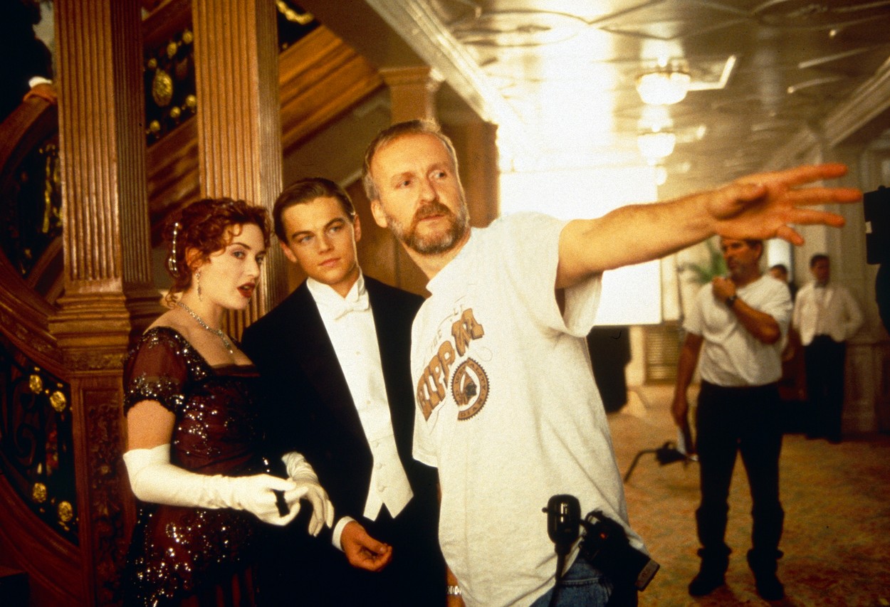 Kate Winslet, Leo Dicaprio și James Cameron se află pe platourile de filmare ale „Titanic” și cei doi actori poartă haine de epocă