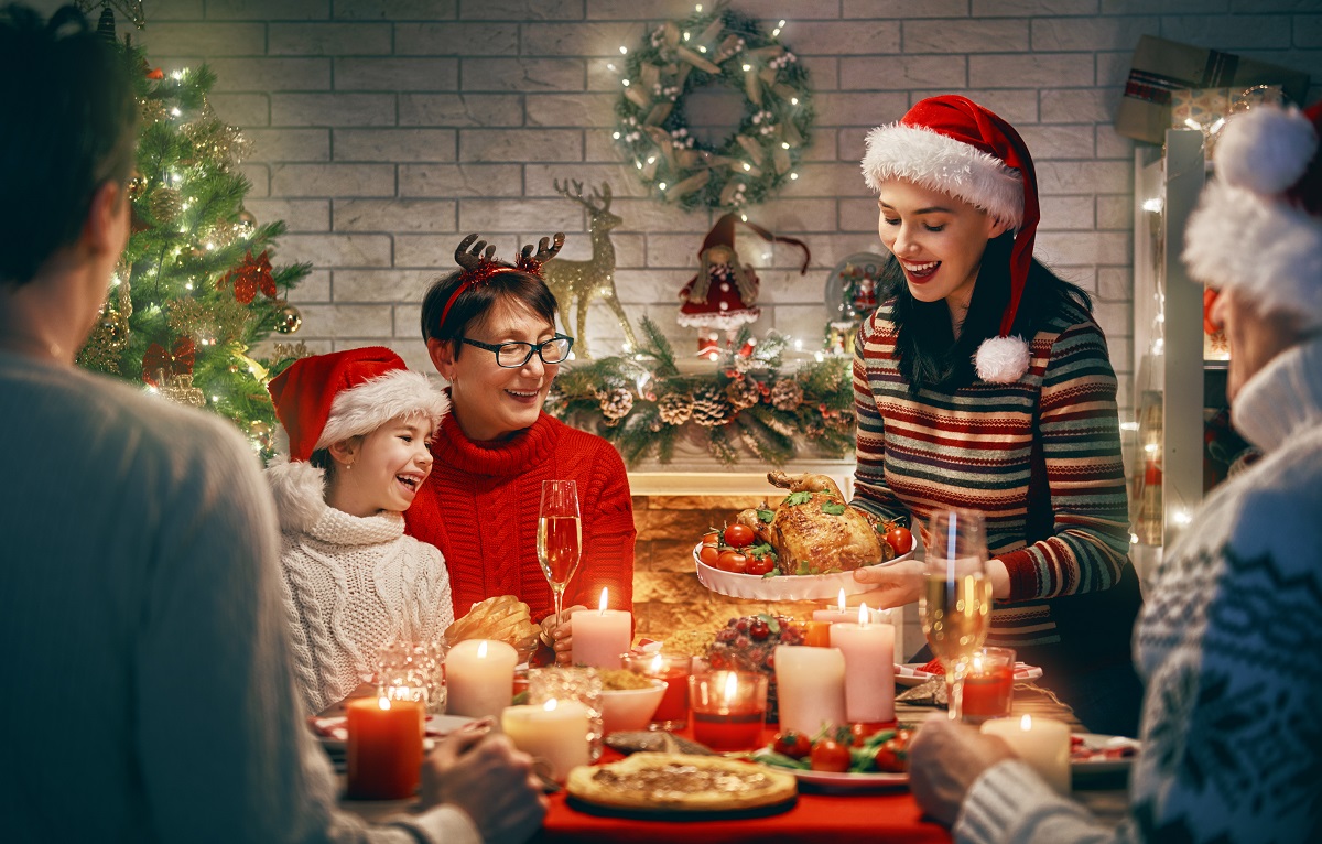 O familie frumoasă care este îmbrăcată de sărbătoare și ia masa de Crăciun împreună