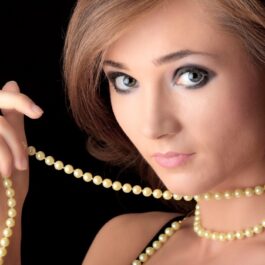 O femeie frumoasă care poartă un colier din perle pentru a ilustra o amuletă norocoasă în funcție de zodie