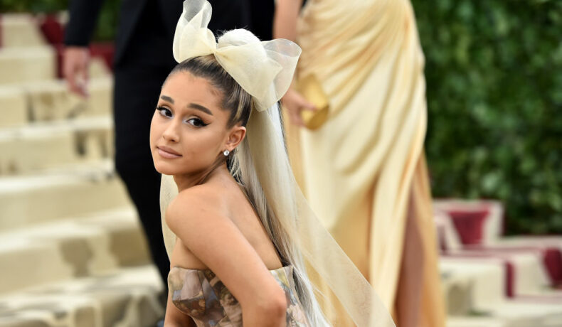 Ariana Grande, la Met Gala în 2018, într-o rochie deschisă la culoare, cu o fundă mare în cap