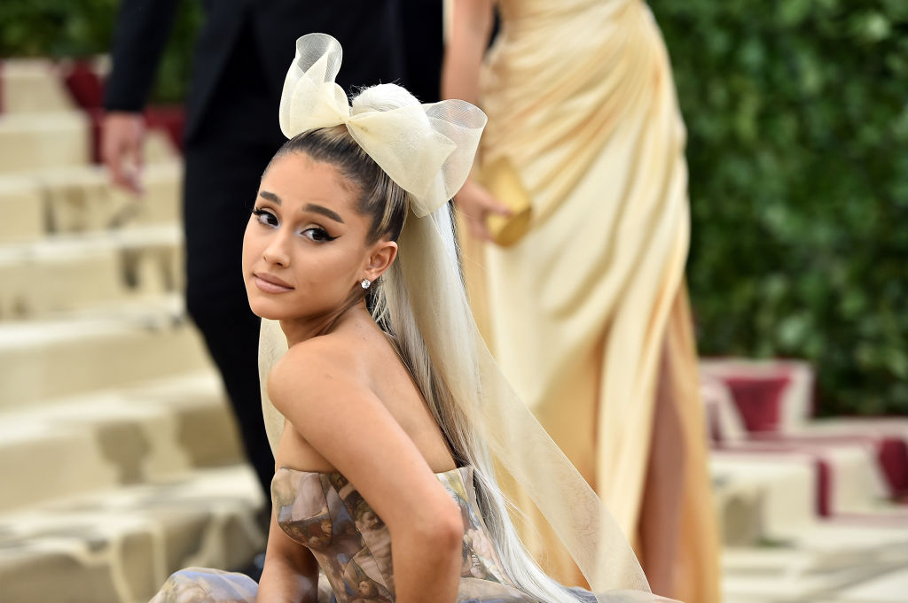 Ariana Grande, la Met Gala în 2018, într-o rochie deschisă la culoare, cu o fundă mare în cap
