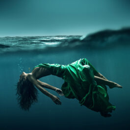 Femeie îmbrăcată într-o rochie verde stă în apă