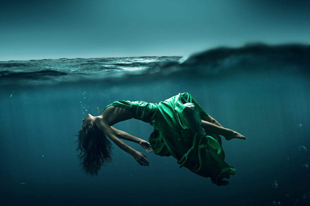 Femeie îmbrăcată într-o rochie verde stă în apă