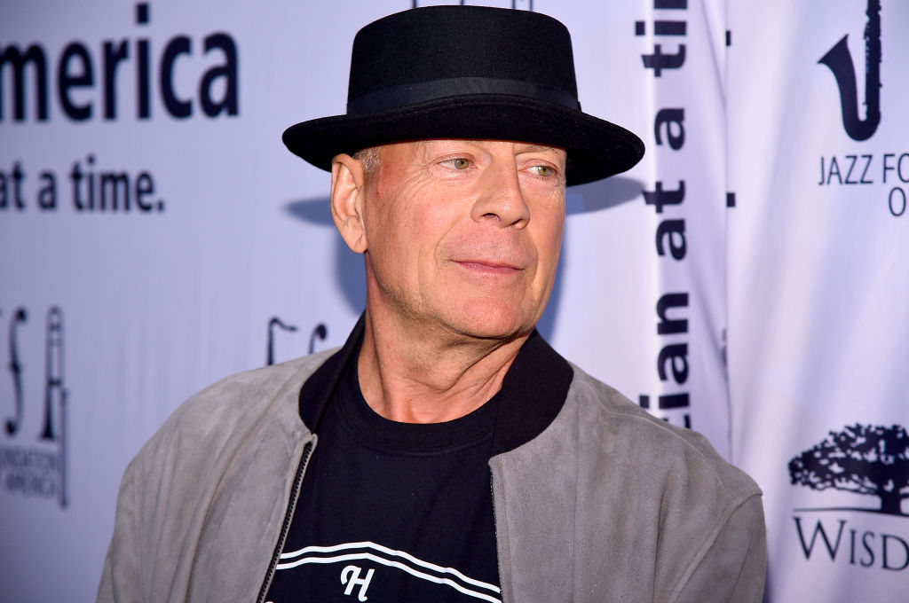 Bruce Willis, cu o pălărie neagră pe cap, la un eveniment, îmbrăcat casual