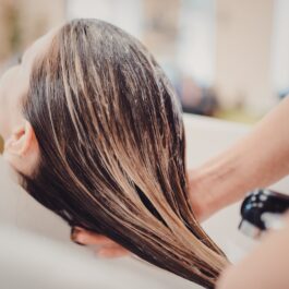 O femeie frumoasă care se află la salon și îi este spălat părul pentru a ilustra când este recomandat să-l cureți