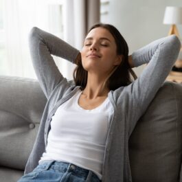 O femeie se întinde pe o canapea și practică medidația, una dintre formele potrivite despre cum să îți îmbunătățești starea mintală în 2023