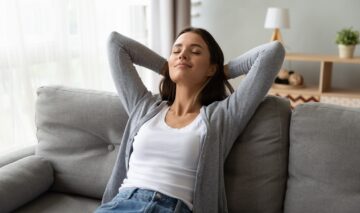 O femeie se întinde pe o canapea și practică medidația, una dintre formele potrivite despre cum să îți îmbunătățești starea mintală în 2023