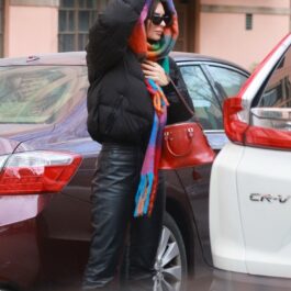 Emily Ratajkowski, cu o eșarfă colorată pe cap, între mașini
