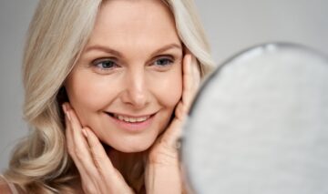 O femeie care se privește în oglindă și aplică câteva sfaturi pentru îngrijirea pielii la menopauză