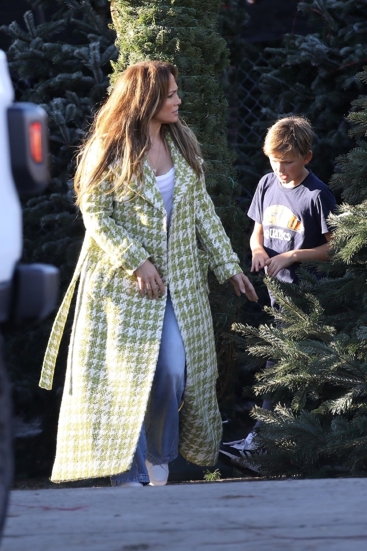 Jennifer Lopez într-un palton alb cu verde în timp ce alege un brad de Crăciun