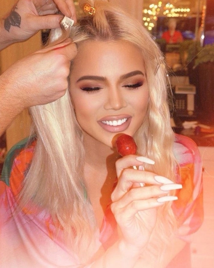 Khloe mănâncă o acadea roșie în timp ce se machiază și își face părul