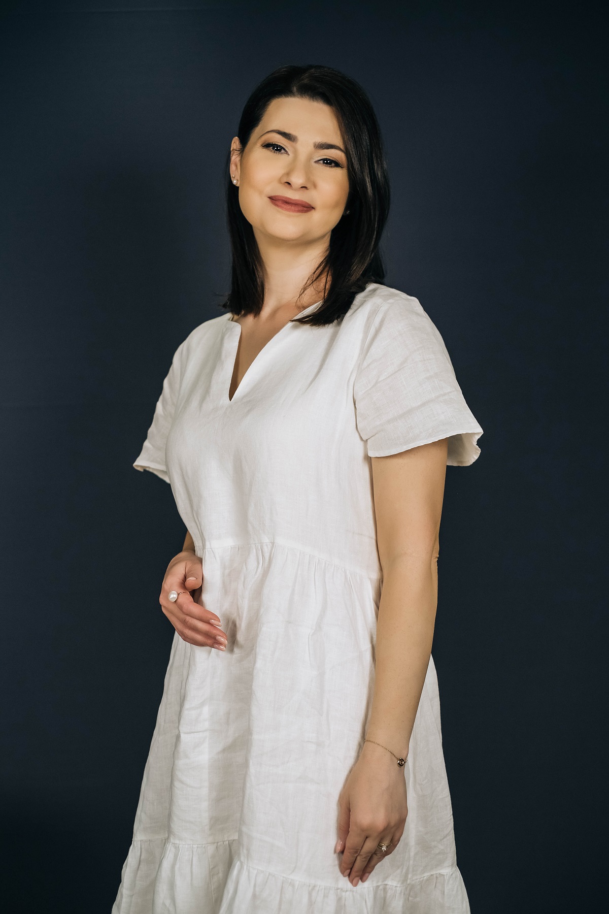 Mihaela Călin într-o rochie albă lungă în timp ce pozează pentru seria DePărinți.ro