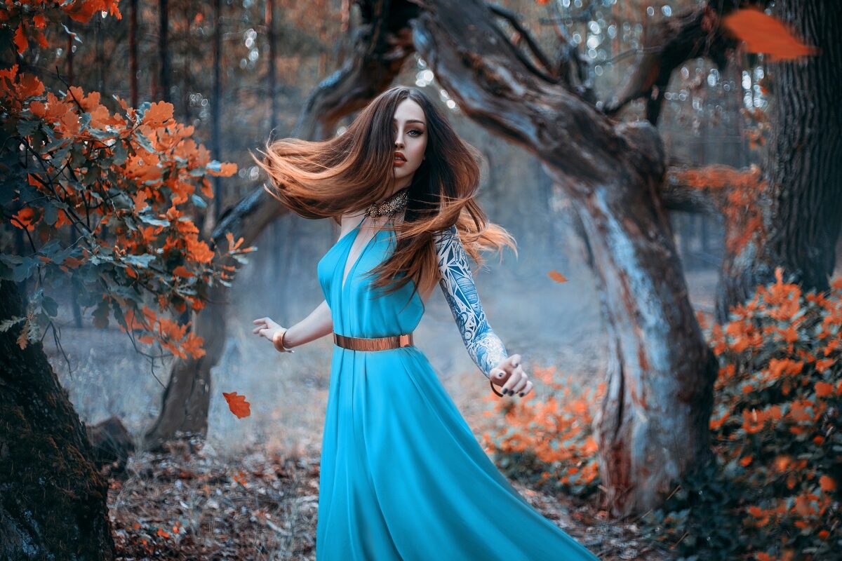 O femeie frumoasă într-o rochie albastră în timp ce dansează în pădure pentru a reprezenta una dintre cele trei zodii ghinioniste în ziua de 12 decembrie 2022