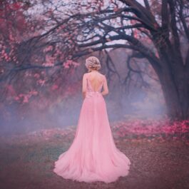 O femeie frumoas care poartă o rochie roz și se află într-o pădure întunecată pentru a ilustra una dintre cele trei zodii ghinioniste în ziua de 18 decembrie 2022