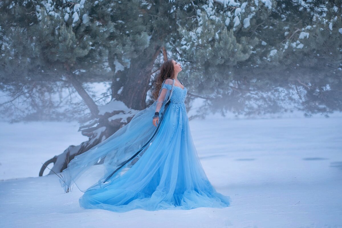 O femeie frumoasă care poartă o rochie albastră și se află într-o pădure cu zăpadă pentru a ilustra una dintre cele trei zodii ghinioniste în ziua de 26 decembrie 2022