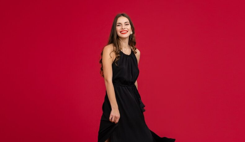 O femeie frumoasă în rochie neagră în timp ce zâmbește pentru a ilustra una dintre cele trei zodii norocoase în ziua de 2 ianuarie 2023