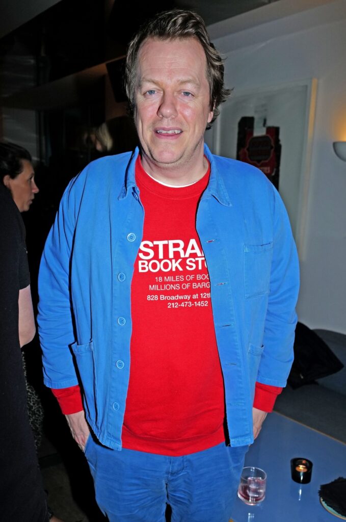 Tom Parker Bowles într-un tricou roșu cu o cămașă albastră la un eveniment public din Londra