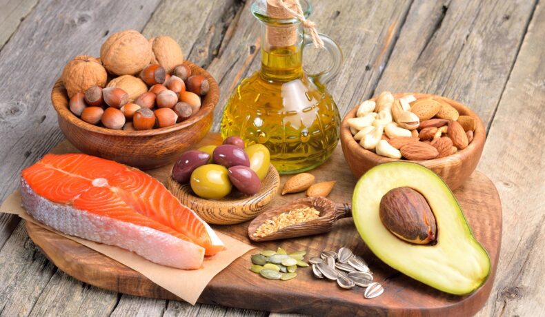 Mai multe alimente bogate în acizi grași omega-3 care mențin sănătatea creierului printre care un file de somon, avocado, uleiuri și migdale